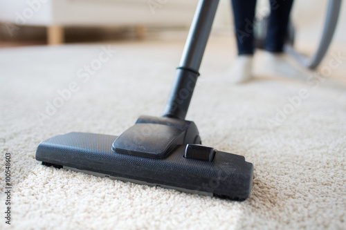 close up of woman legs with vacuum cleaner at home photo