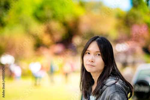 Closeup portrait of pretty and young Asian lady woman with blurred outdoor park background 