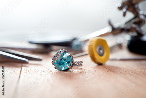 Desktop jeweler. silver ring with blue stone on the table with jewelry tools