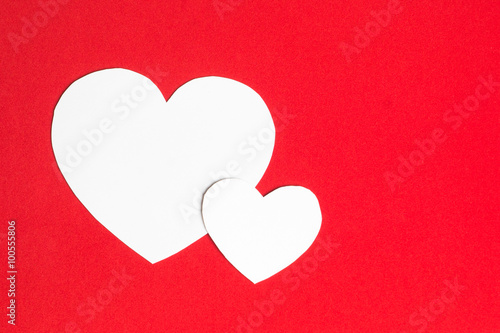 Two paper hearts together on red background