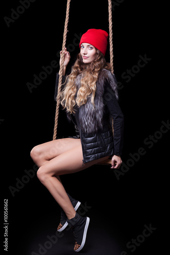 Portrait of beautiful model in red hat and jacket posing on rope