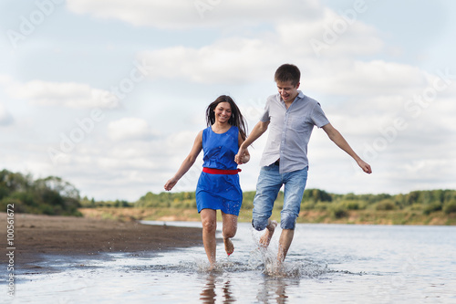 A young couple walks along the beach.