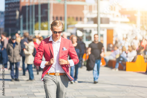 Fashioned young man in Oslo walking on crowded sidewalk