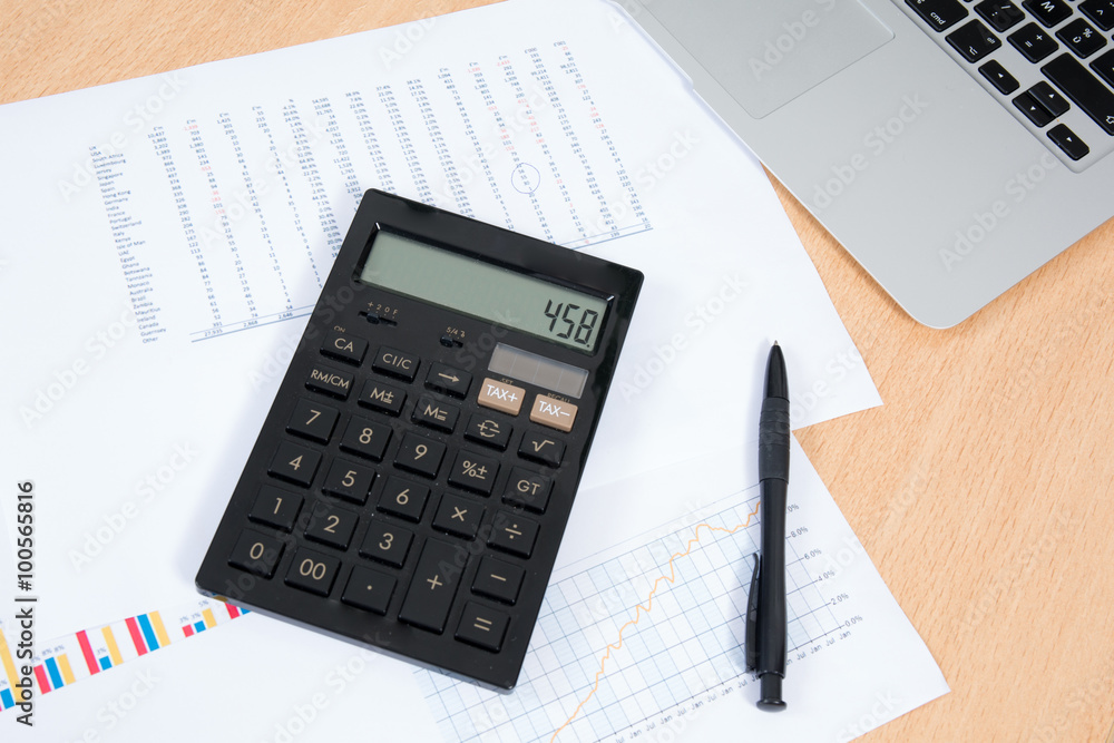 Laptop with business charts and calculator on the desk Laptop with business charts and calculator on the desk