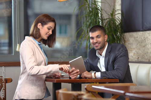 Two young business people using digital tablet on a meeting at coffee shop