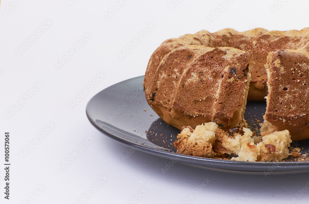 cake with raisins on dark ceramic plate separated over white background cake with raisins on dark ceramic plate separated over white background