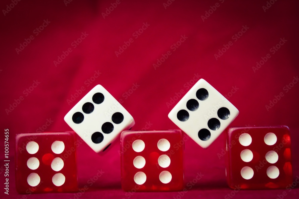 A set of die all showing sixes against red felt A set of die all showing sixes against red felt