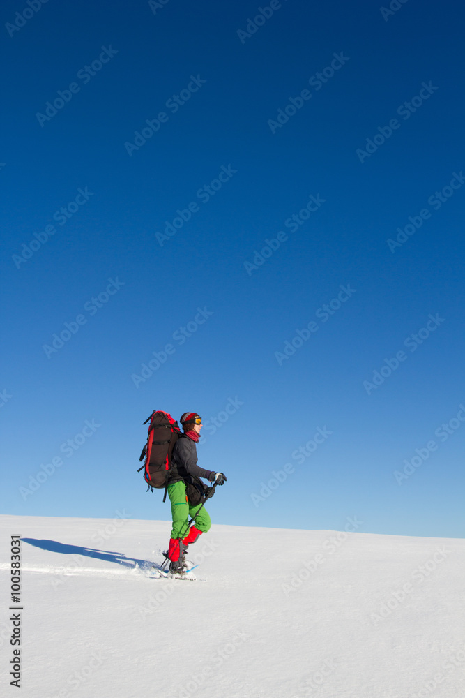 Winter hiking in the mountains on snowshoes with a backpack and tent.