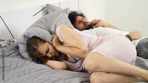 woman hiding her head under the pillow while sleeping with a man slow motion photo