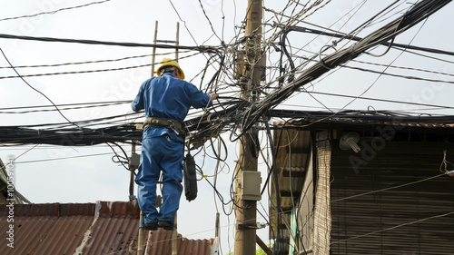 electrician fixing, repairing messy electric cables in hanoi slums, vietnam