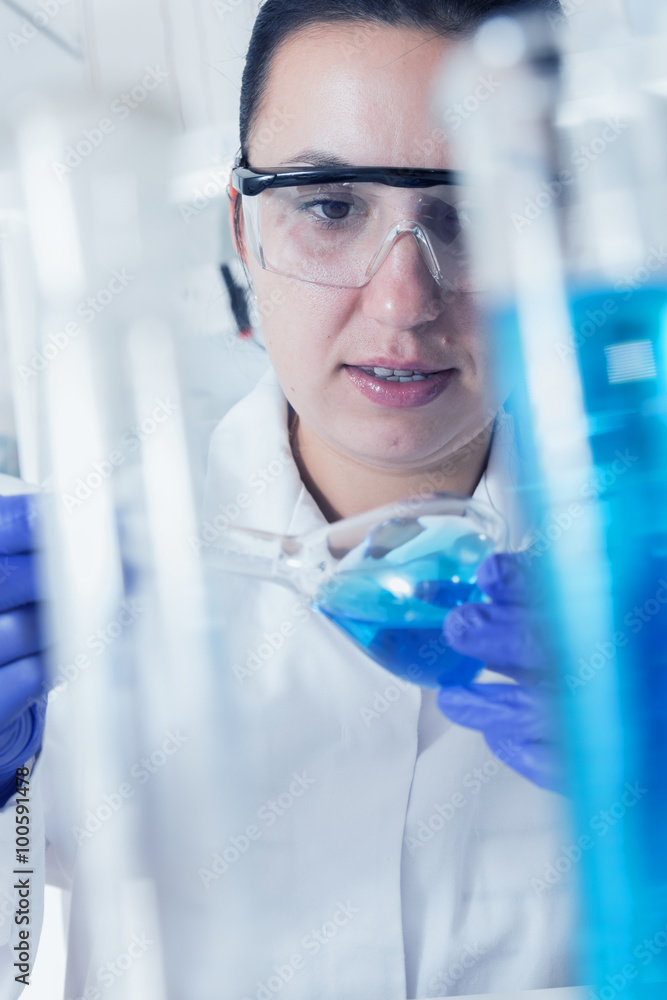 Young Female Scientist Analyzing Sample In Laboratory.laboratory assistant analyzing a sample.