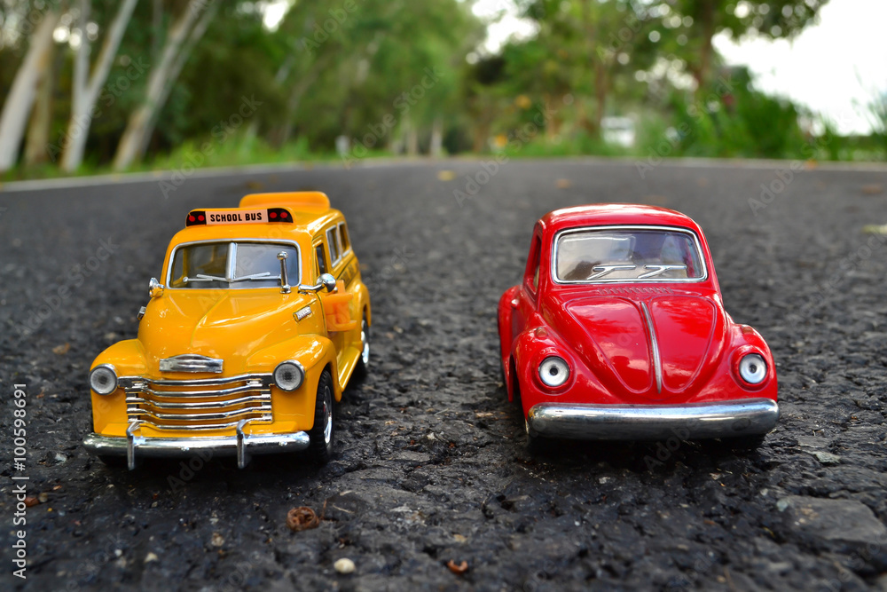 Red toy car and school bus park couple on the road Red toy car and school bus park couple on the road