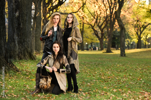 Three beautiful young models in autumn elegant clothes posing at Central Park, New York location, for fall fashion photo shoot.