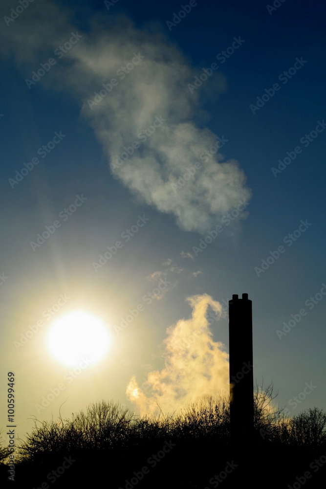 Smoke from factory with big chimney against blue sky