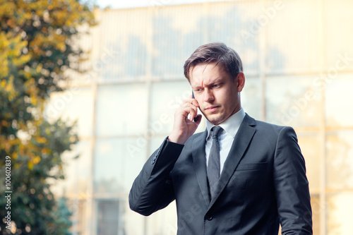 Thoughtful young businessman talking on the mobile phone