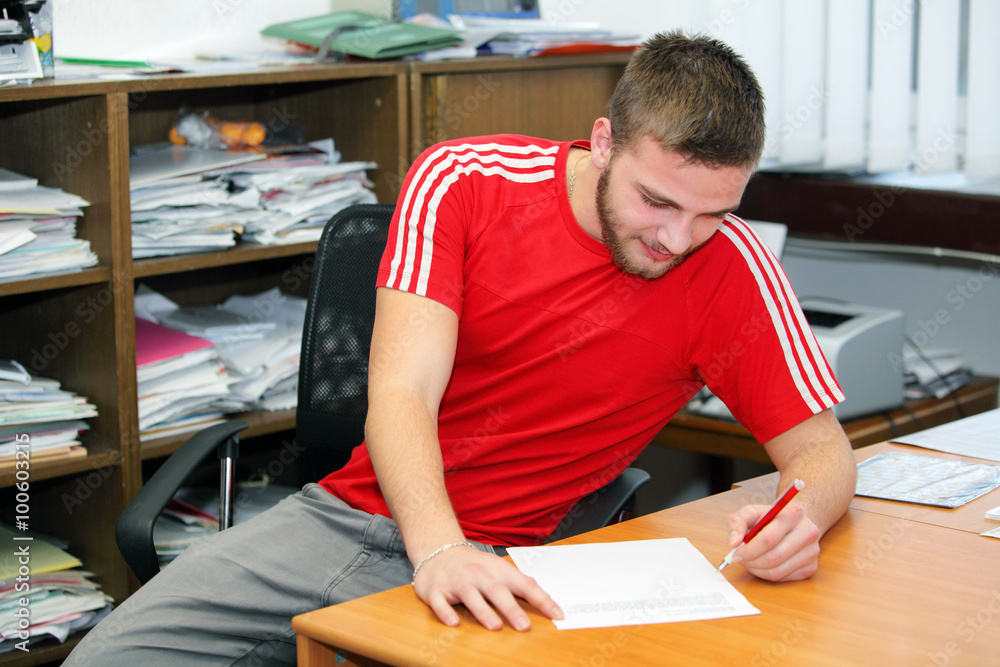 Attractive young man writes a letter by hand Attractive young man writes a letter by hand
