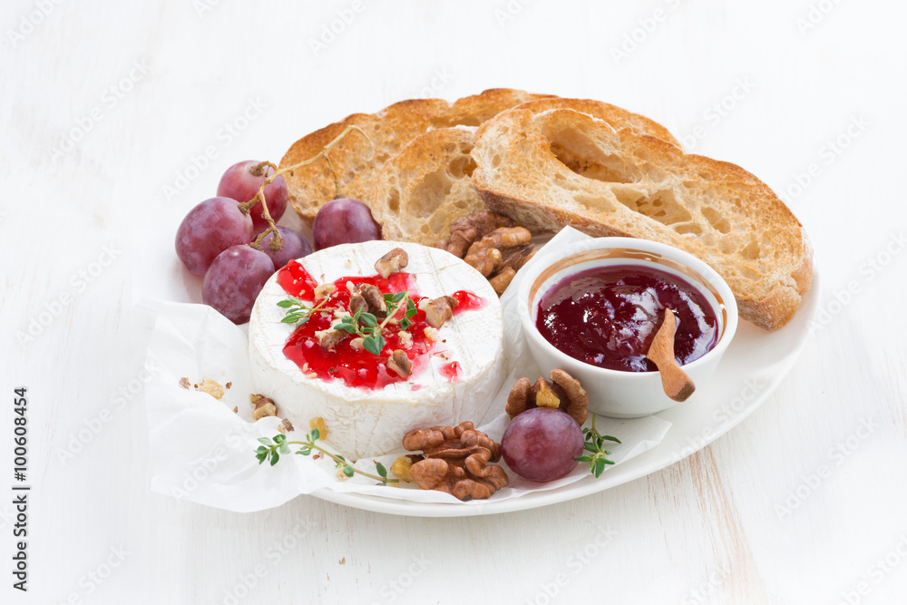 camembert with berry jam and toast on a white wooden background