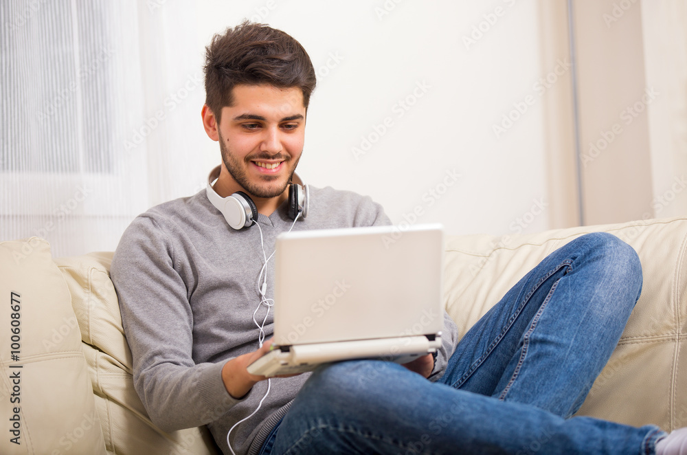 Man using laptop computer, sitting on sofa