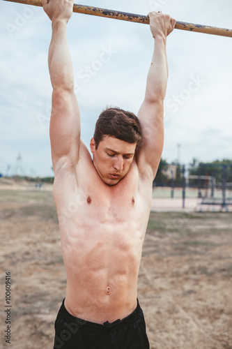 man hanging on the horizontal bar