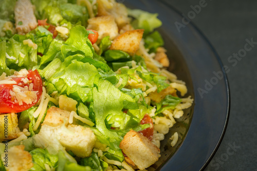 Caesar salad made of fresh vegetables on dark background. Selective focus.