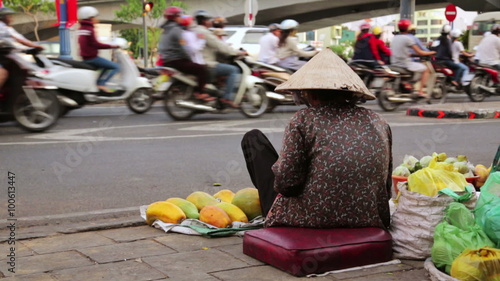 Vendor woman sitting and selling fruits on heavy hanoi traffic