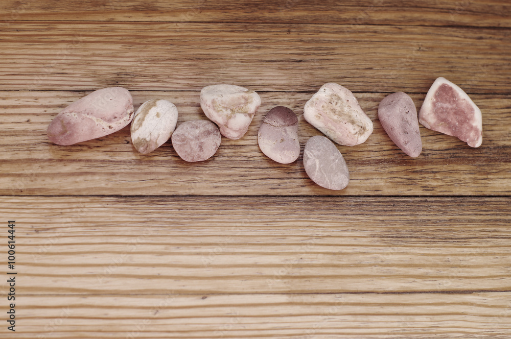 small sea stones of pale pink shades on wooden background, local focus, shallow DOF 