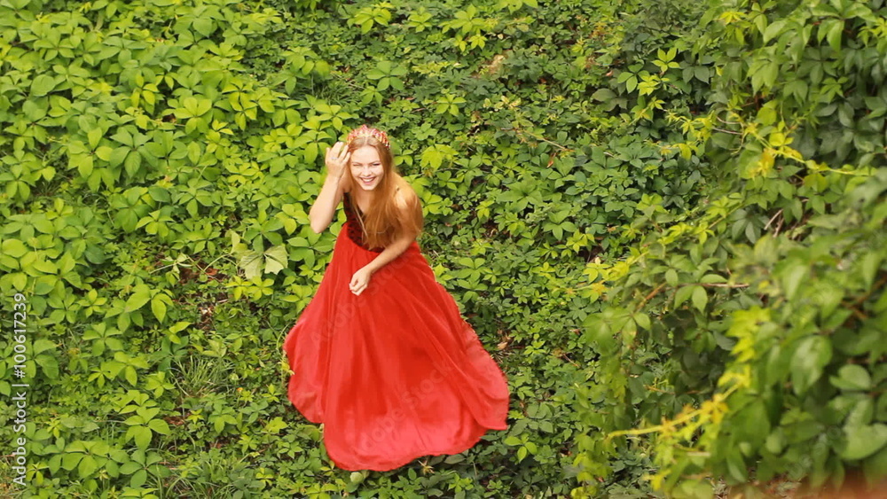 Beautiful young woman in fashion red dress posing on the green grape