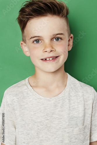 Young kid smiling at camera against green background