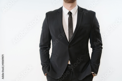 part of business man body in black suit with hands in pockets on