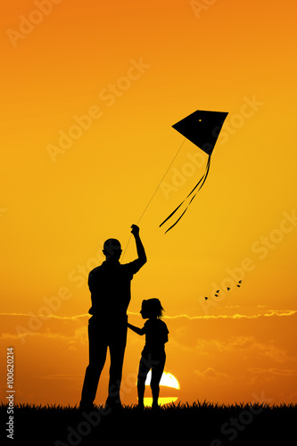 father and son with kite at sunset