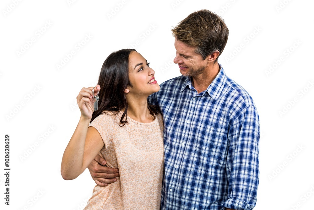 Cheerful couple embracing while holding keys Cheerful couple embracing while holding keys