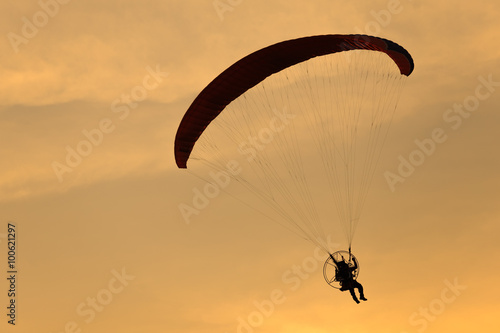 Paramotor flying in the sunset sky, Silhouette shot.