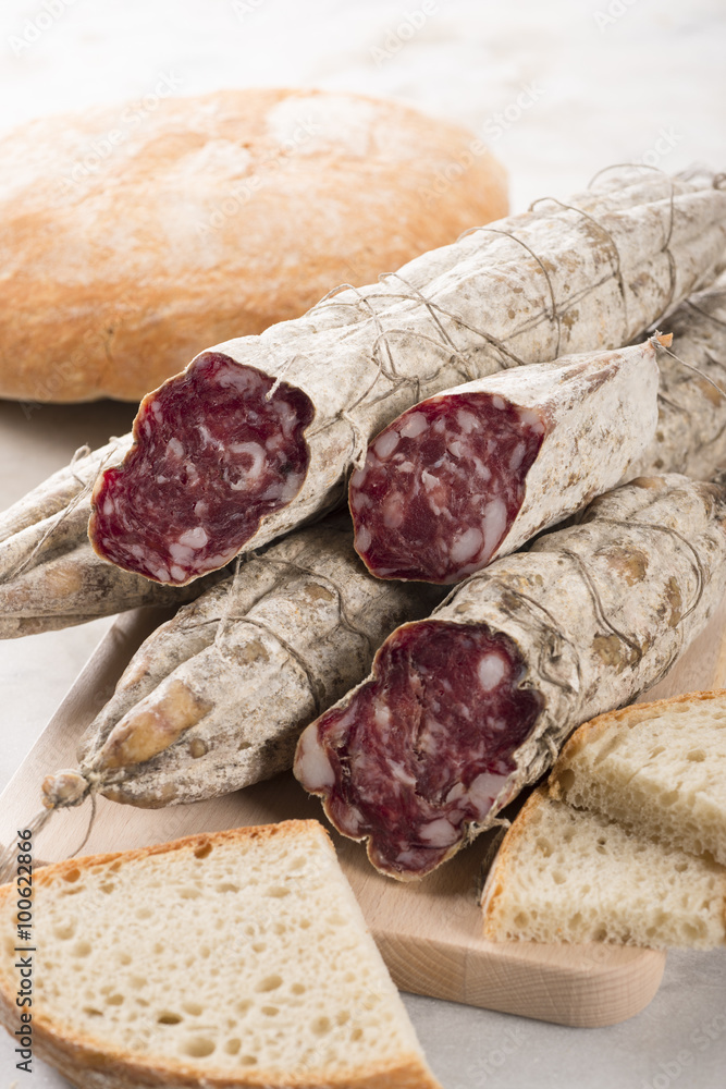 Some Italian sausages arranged on a cutting board with bread, selective focus. Some Italian sausages arranged on a cutting board with bread, selective focus.