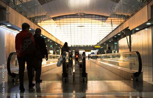 Silhouettes passengers walk toward escalator in the aieport