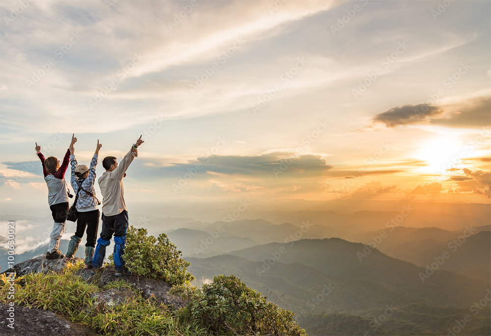 Naklejka premium Szczęśliwi ludzie na górze góry cieszący się dolinnego widok podczas gdy słońce ustawia.
