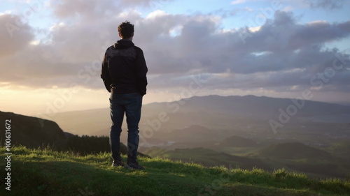 Young caucasian man looking down from the montain towards the ocean