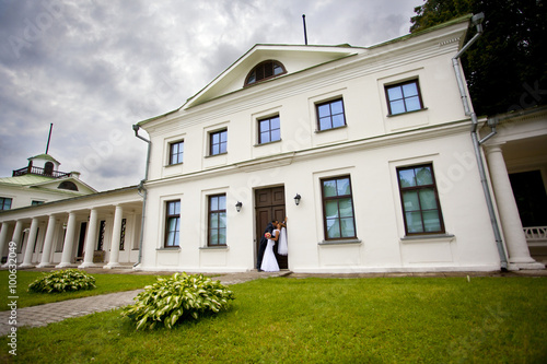 Жених и невеста целуются в дверях усадьбы  © bellefotos