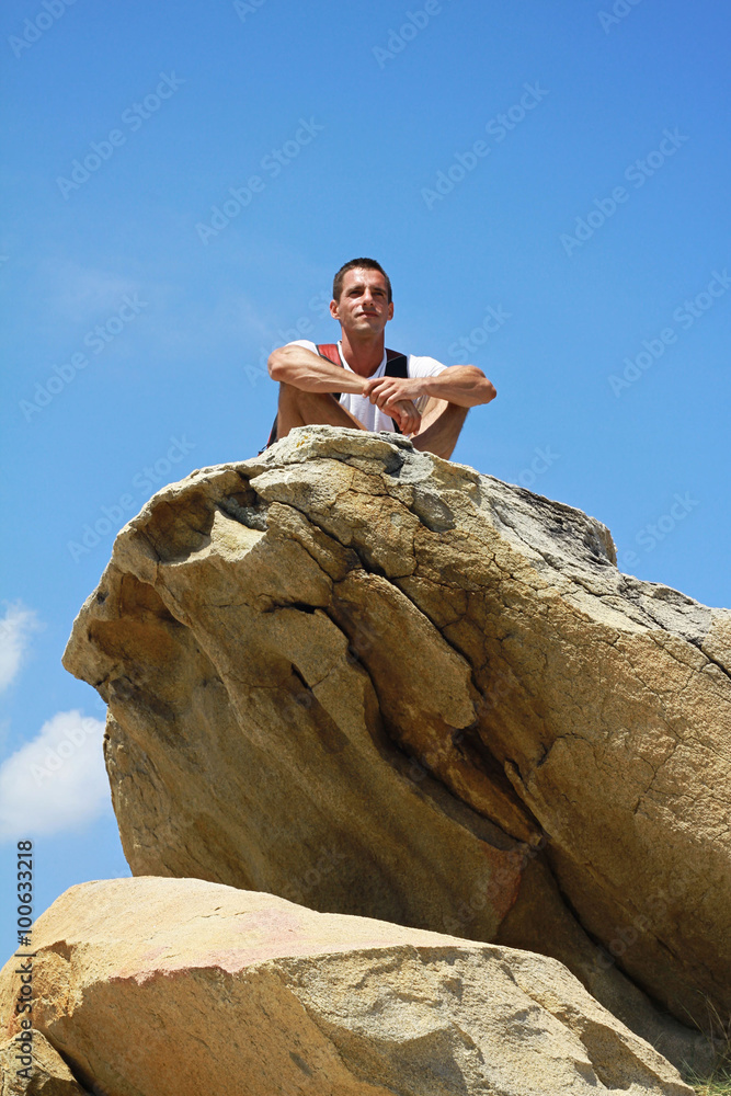 Young man sitting and Having a Rest on top of a mountai n