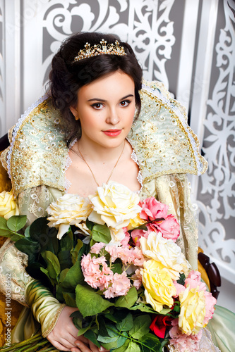 beautiful haughty queen in royal dress.Princess holding a large bouquet of flowers. Queen in the interior