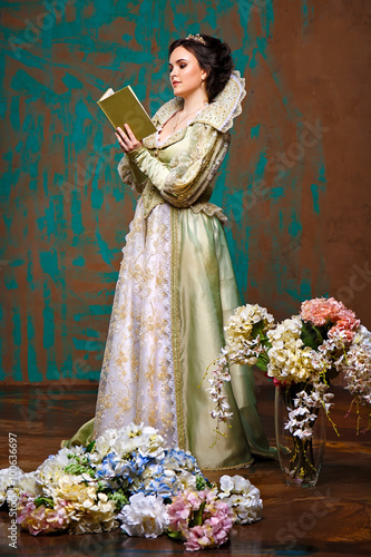queen in royal dress reading a book. actress with an old dress