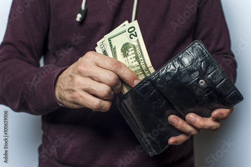 Man in a sweatshirt holds wallet with money