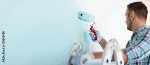 close up of male in gloves holding painting roller photo