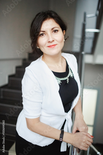 Pretty brunette business woman with kind eyes leaning forward posing on stairs of office building, wearing white jacket over tight black dress. Positive look, candid portrait. Consultations, support. Free Download Pretty brunette business woman with kind eyes leaning forward posing on stairs of office building, wearing white jacket over tight black dress. Positive look, candid portrait. Consultations, support. - GFXLoad