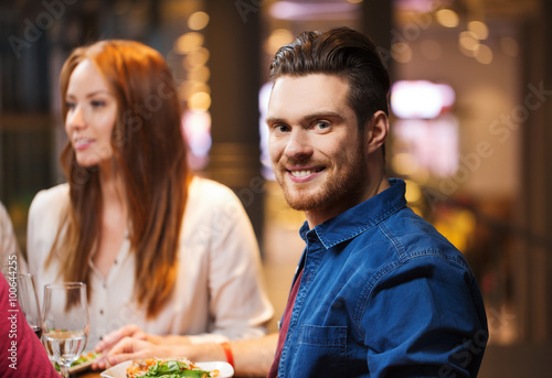 happy man with friends having dinner at restaurant