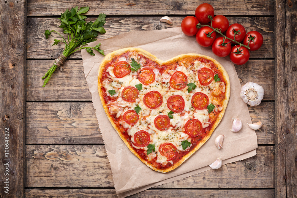 Valentines day heart shaped pizza margherita vegetarian love concept with mozzarella. tomatoes, parsley and garlic on vintage wooden table background.