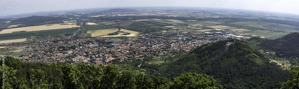 Fototapeta premium Teen going on a zip line adventure above a valley. Teen boy going on a zip line adventure above a valley. Forest lay below and in the distance there are cultivated fields.