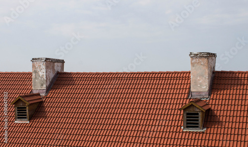 Red roof and two chimney against the sky