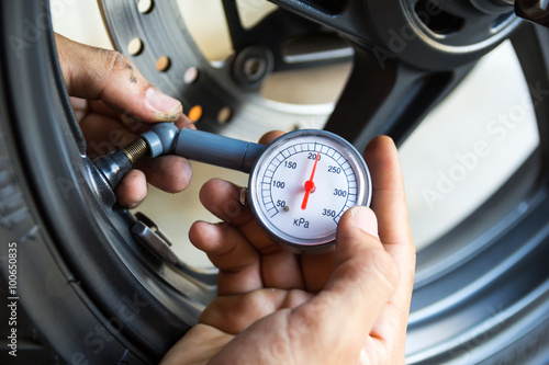 Hand holding pressure gauge for motorbike tyre pressure measurem