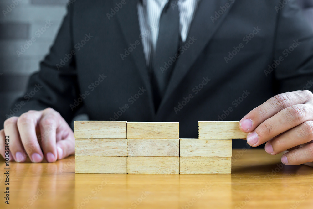 Businessman make a building with wood blocks Businessman make a building with wood blocks