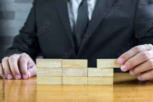 Businessman make a building with wood blocks